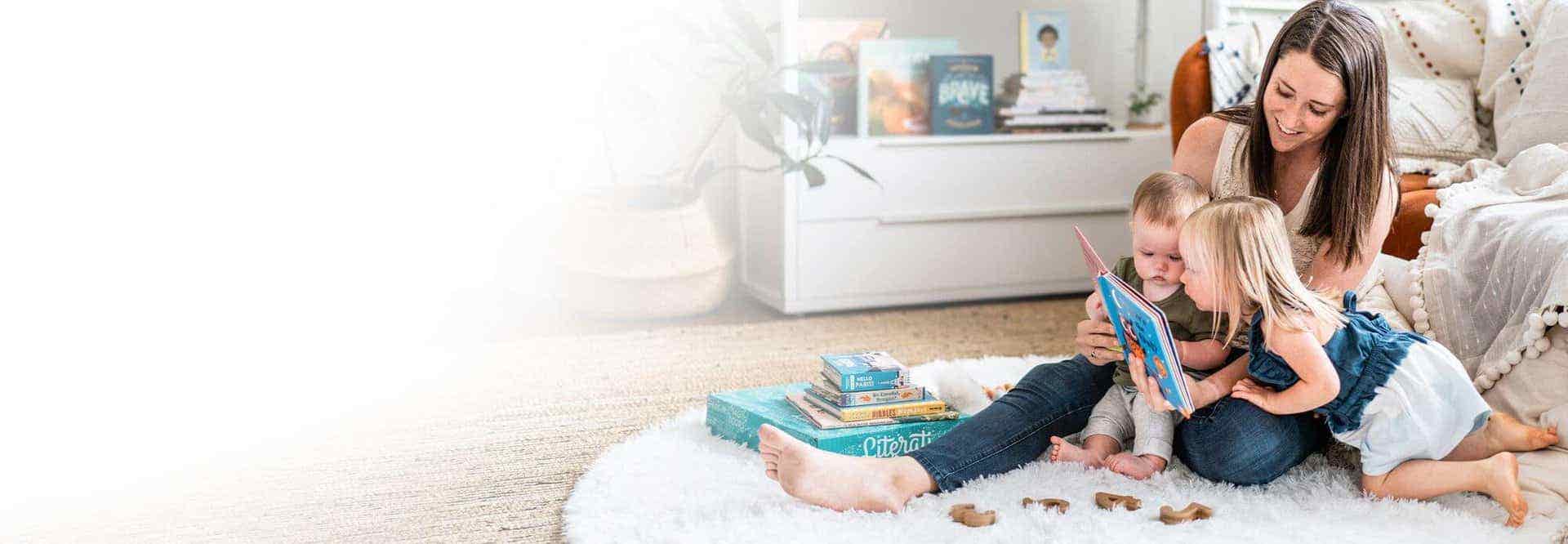 Mother reads with two small children on the floor of living room.