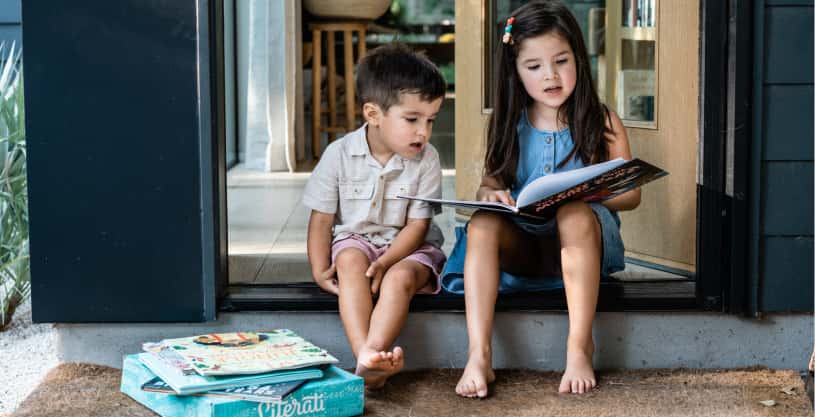 Two kids sitting and reading a book