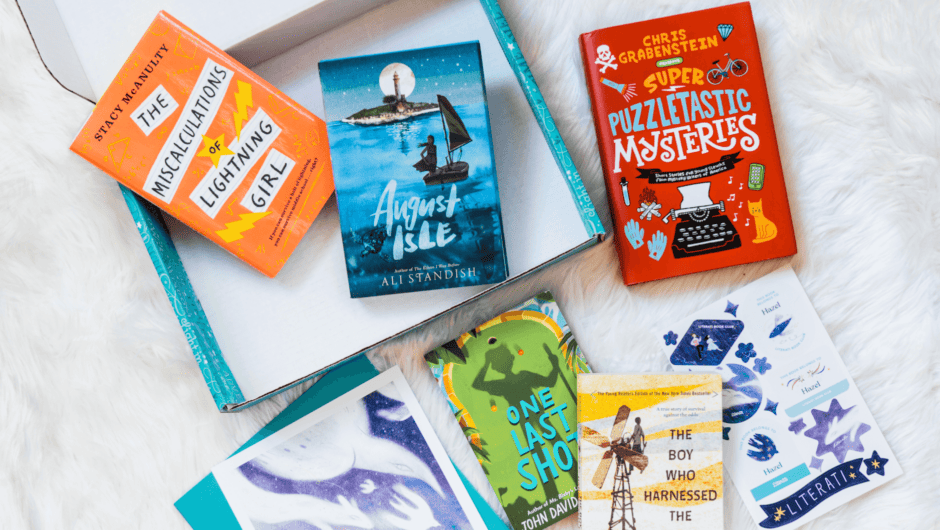 Open box with two chapter books, and 3 more scattered around on a fuzzy white rug, with artwork and stickers.