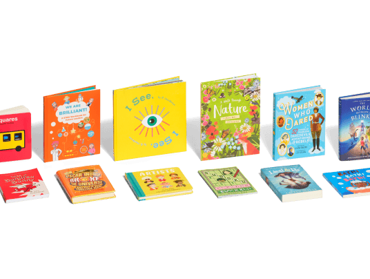 Rainbow arrangement of books standing and laying down for all ages.