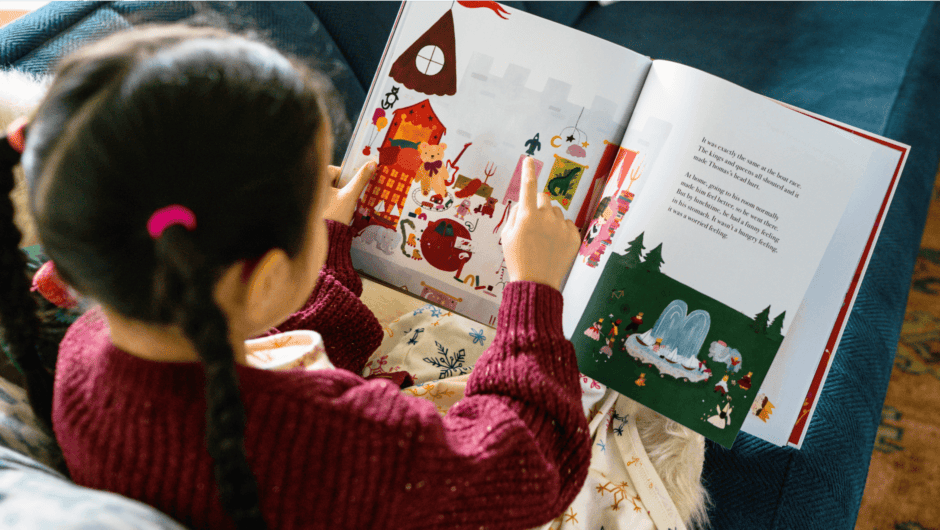 Girl pointing to book sitting on couch